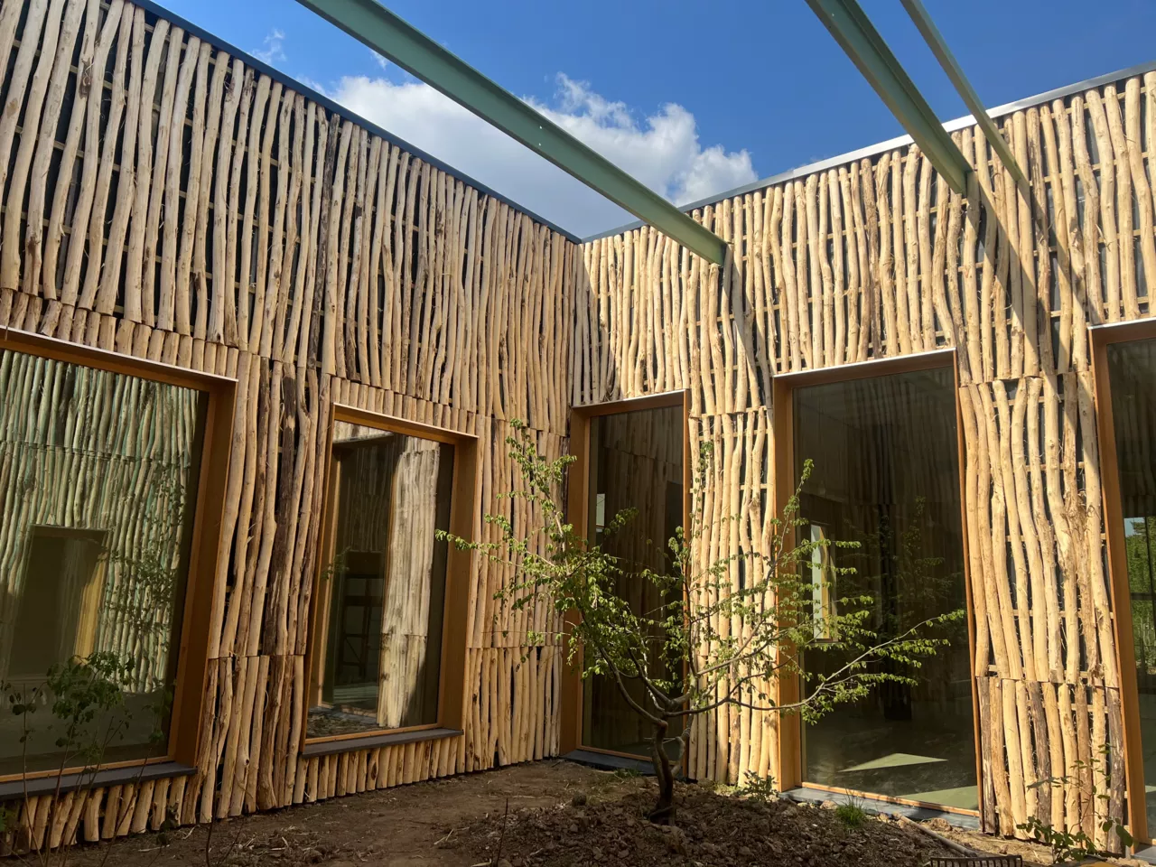Façade du bâtiment démonstrateur de Noeux-environnement réalisée en bois brut non équarri, illustrant l’utilisation de matériaux biosourcés locaux et une architecture inspirée de la nature.
